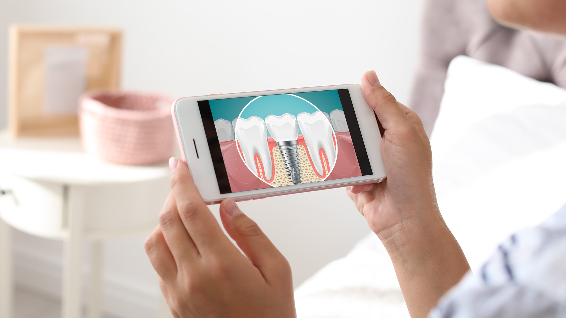 A person holding a smartphone displaying an image of a tooth with a magnified view of its root and gumline, suggesting dental health or care.