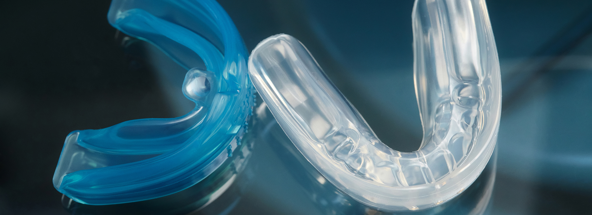 An image of a transparent blue toothbrush with bristles and its packaging, displayed against a blurred background.