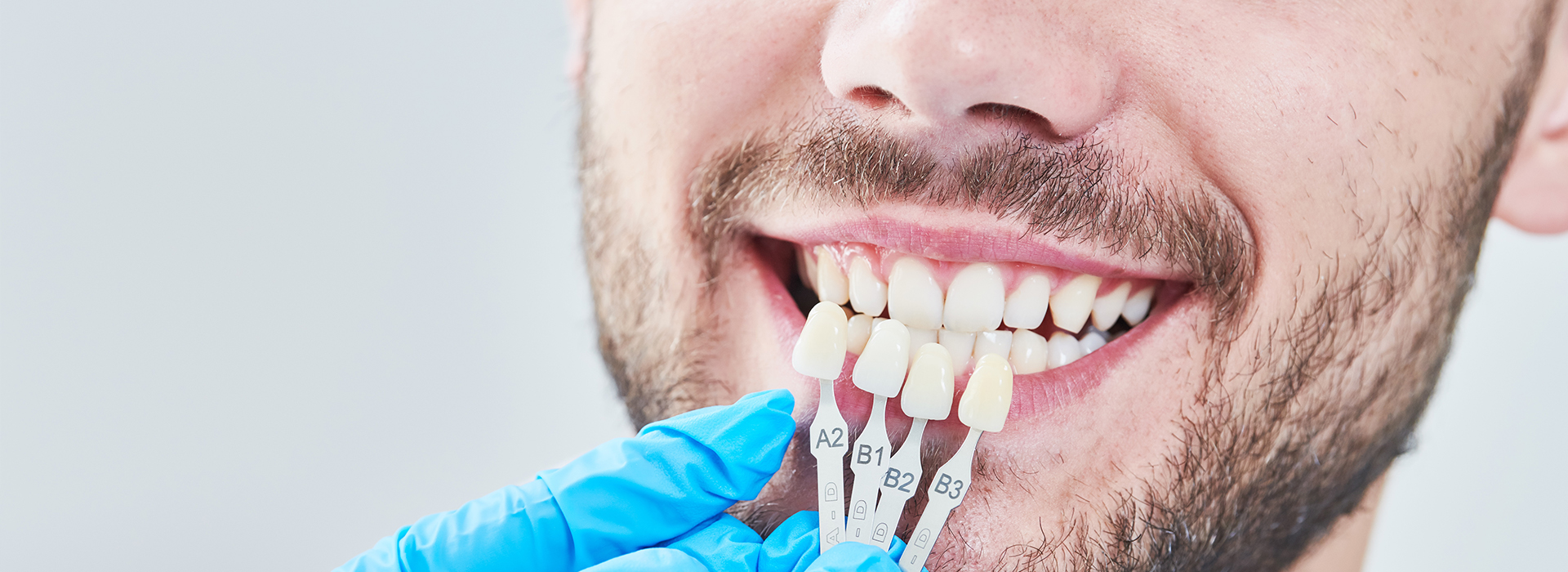 A man is shown with a tooth in his mouth, being examined by a dental professional using a magnifying glass.