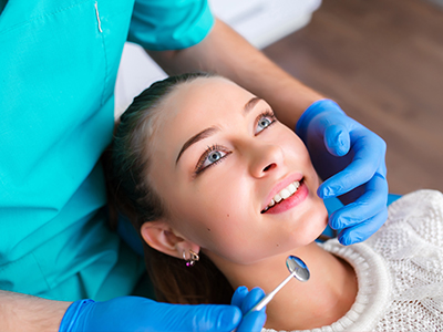 An image depicts a dental professional performing a procedure on a patient s teeth, with the patient smiling and looking at the camera.
